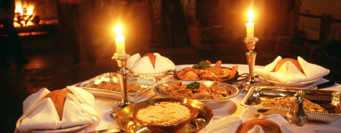 A historic meal laid out on a table and lit by candlelight
